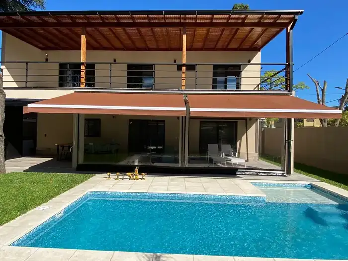 Galería con techado y toldo retráctil junto a la pileta
