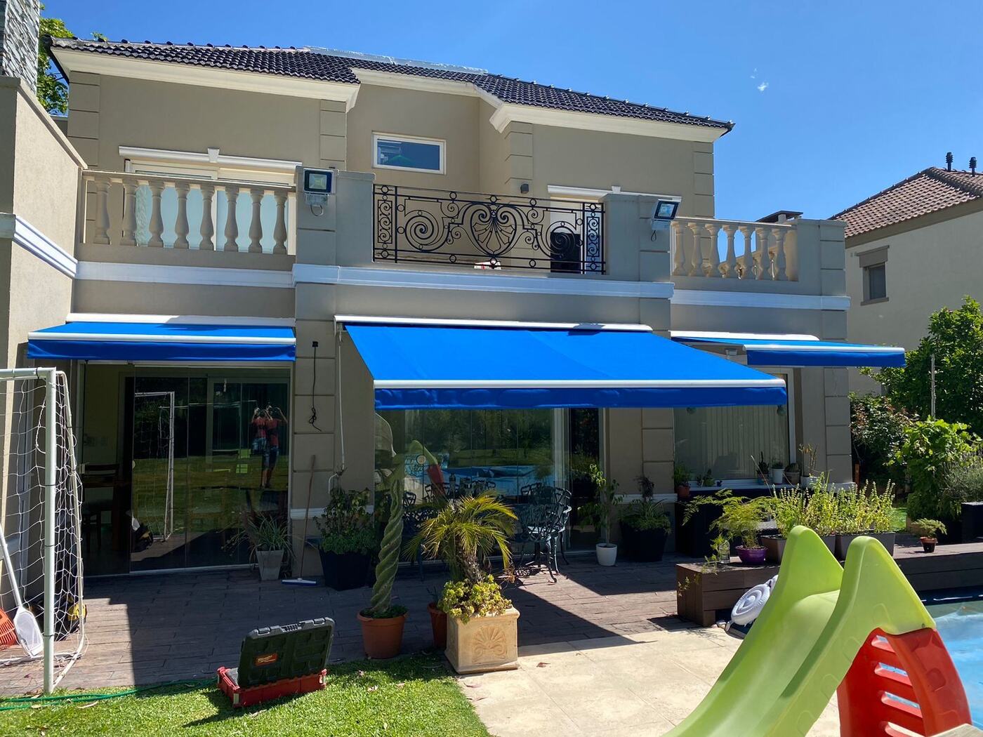 Toldo retráctil instalado sobre la galería de una casa con pileta