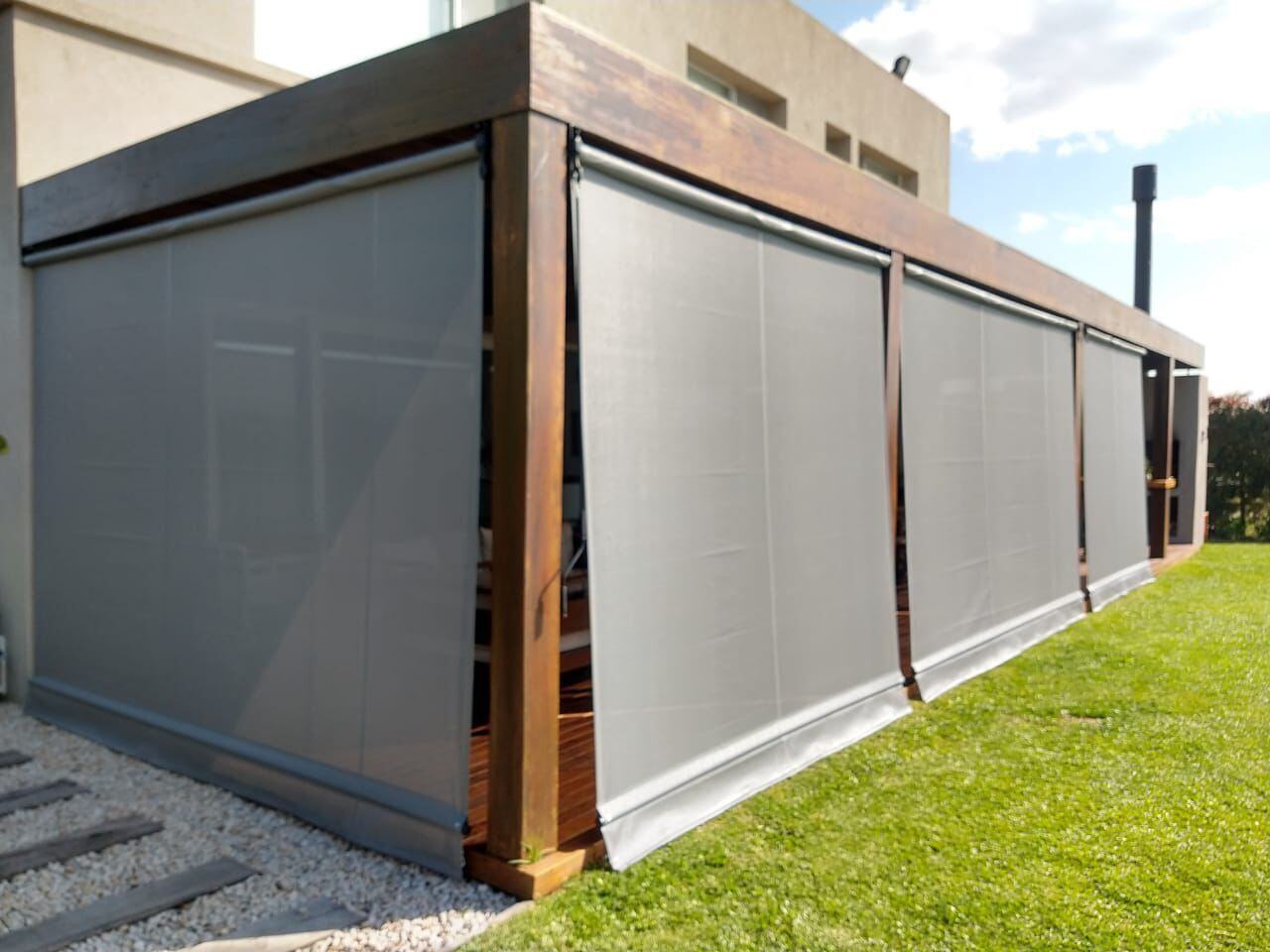 Galería de una casa cerrada con toldos verticales screen